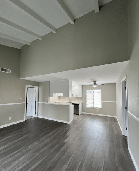 A room with a wooden floor and a window with blinds.